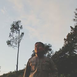 Low angle portrait of man standing against sky