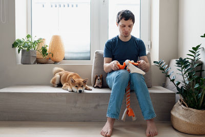 Adult man making diy homemade educational toys for dogs using a tutorial from the internet