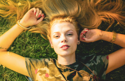 High angle portrait of beautiful young woman lying on grass