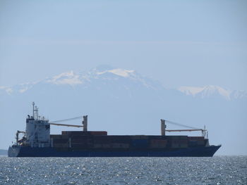 Ship sailing at sea against mountain