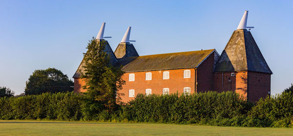 Trees and buildings against clear blue sky