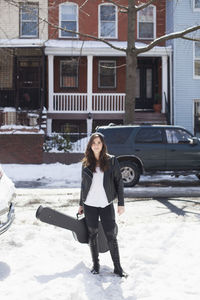 Young woman carrying a guitar case through the snow