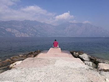 Rear view of man looking at sea against sky