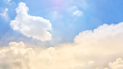 Low angle view of sunlight streaming through clouds