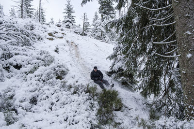 Full length of man sitting on snow covered land during winter