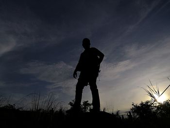 Silhouette man standing on field against sky during sunset