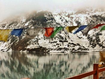 Reflection of flags on lake against mountain