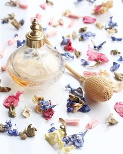 Close-up of perfume bottle and petals on table