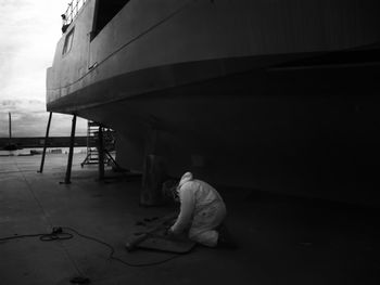 Full length of worker repairing boat part at port