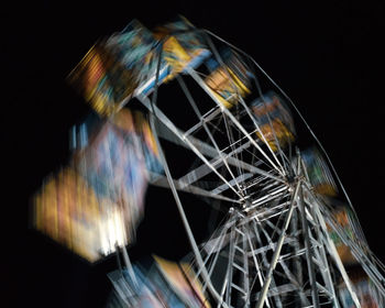 Low angle view of illuminated ferris wheel against black background