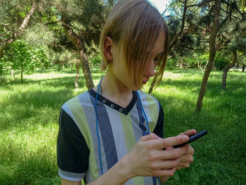 Full length of girl holding mobile phone in field