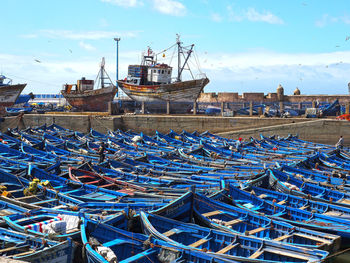 Fishing boats moored at harbor against blue sky