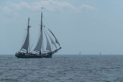 Ship sailing on sea against cloudy sky