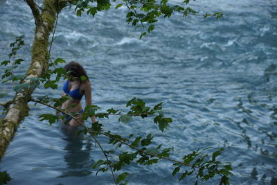 Woman standing by sea against plants