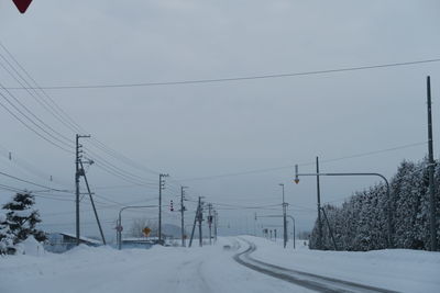 Electricity pylon by snowcapped mountain against sky