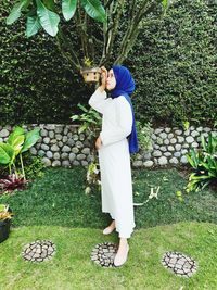 Young woman standing by plants at park