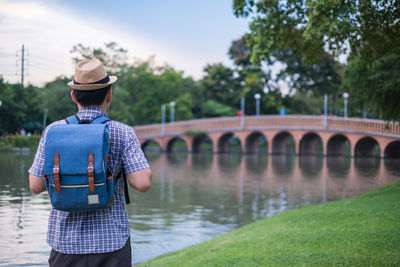 Rear view of man standing on bridge over river