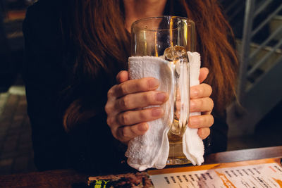 Midsection of woman holding glass at table in restaurant