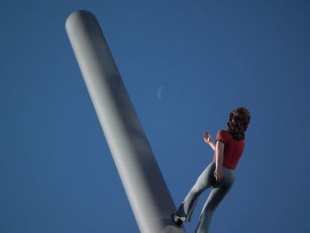 Low angle view of woman against blue sky