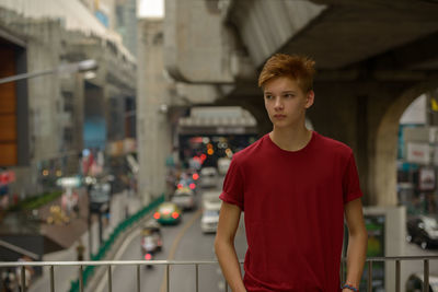 Portrait of teenage boy standing against built structure