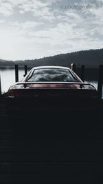 Rear view of boat in lake against cloudy sky