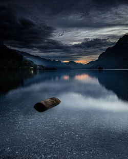 Scenic view of rocks in lake against sky at dusk