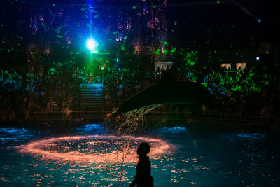 Man standing in illuminated city during rainy season at night