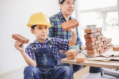 Father teaching son to make brick wall at workshop