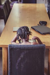 Rear view of woman sitting on table