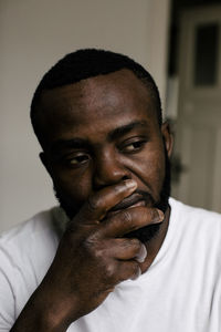 Mentally ill man with hand on chin looking away at home