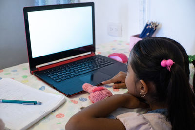 Low angle view of girl using laptop on table at home