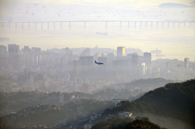 Airplane flying over city during sunrise