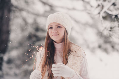 Portrait of teenager girl holding sparkler standing outdoors