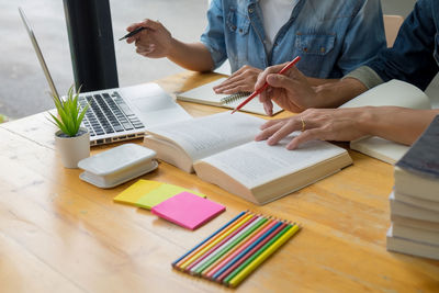 Midsection of woman reading book on table