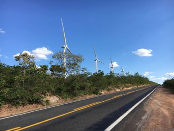 Road by trees against blue sky