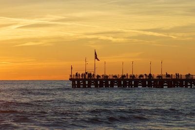 Silhouette pier over sea against sky during sunset