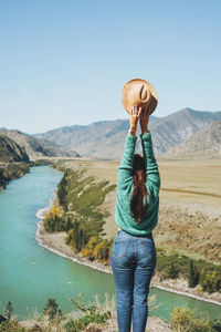 Young brunette woman traveller in sweater with felt hat on background of turquoise katun river