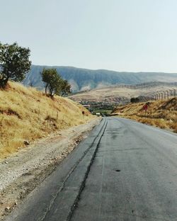 Empty road along landscape against clear sky