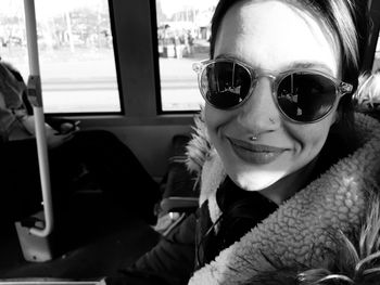 Portrait of smiling woman wearing sunglasses sitting in bus