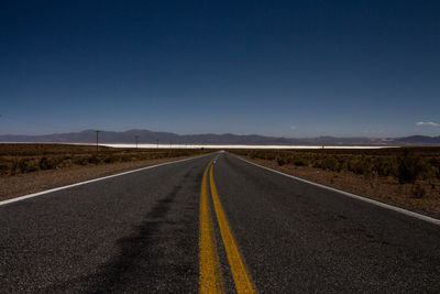 Empty road against clear blue sky