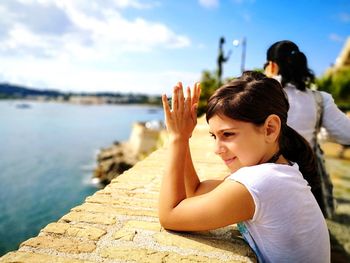 Side view of girl standing at railing on promenade against sky