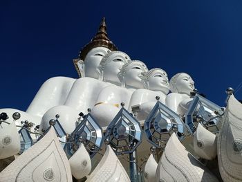 Low angle view of sculptures on building against blue sky
