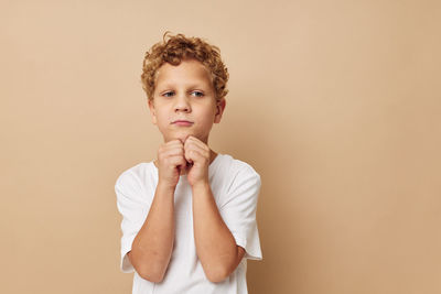 Boy gesturing against beige background