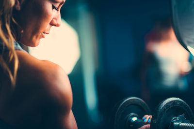 Close-up of mid adult woman lifting dumbbell