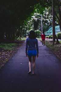 Rear view of woman walking on footpath in city