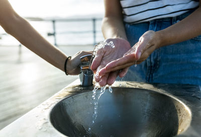 Woman washing hands at drinking fountain