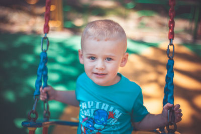 Portrait of smiling boy on swing at playground