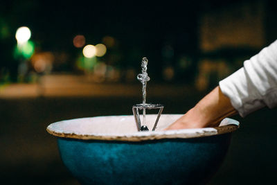 Person using drinking fountain at night