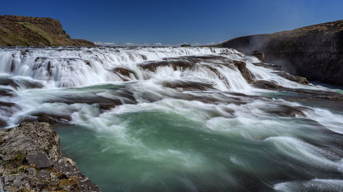 Scenic view of waterfall against sky