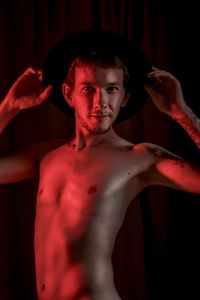 Portrait of shirtless young man standing against wall
